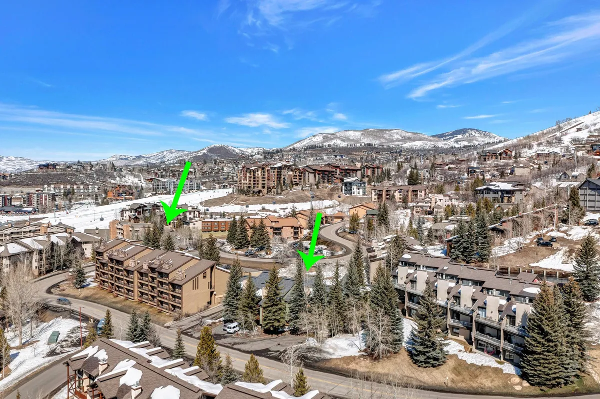 A sweeping view of the mountain landscape with residential buildings, tree lines, and winding roads, suggesting easy access to community activities and events within the neighborhood and beyond.