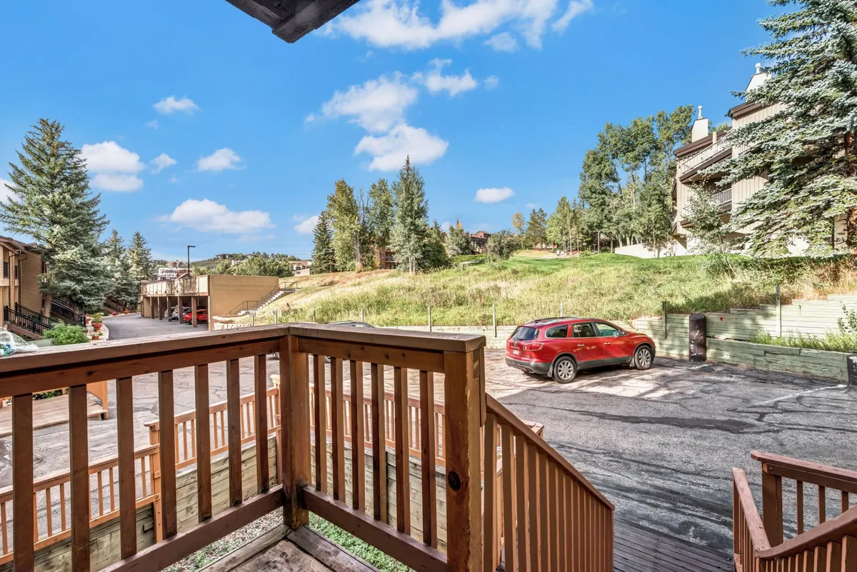 A tranquil exterior image of a balcony with wooden railing overlooking a green landscape, perfect for relaxing with company and enjoying the natural beauty of the area.